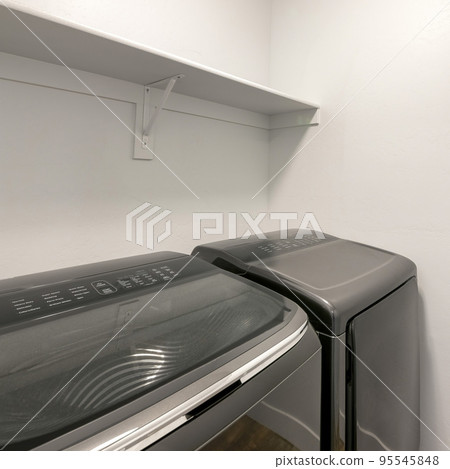 Square Two laundry appliances with reflective glass inside a laundry room 95545848