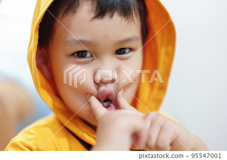 The cute eyes of an Asian boy wearing a hat is smiling and playing with innocence 95547001