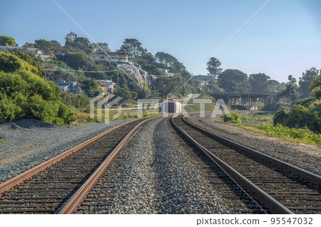 Close up of a railroad with rusty tracks along cliff homes against blue sky 95547032