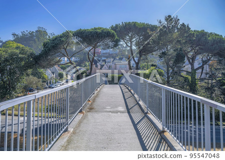Narrow paved walkway overlooking houses and blue sky on a sunny day Narrow paved walkway overlooking houses and blue sky on a sunny day 95547048