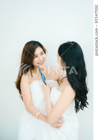 lgbtq, lgbt concept, homosexuality, portrait of two asian women posing happy together and showing love for each other while brushing teeth. lgbtq, lgbt concept, homosexuality, portrait of two asian women posing happy together and showing love for each other while brushing teeth. 95547092