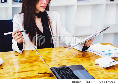 Young economists or accountants or financiers and investors are reviewing budget documents and using computers to study impact and risk assessments on corporate investment management 95547095