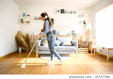 House cleaning with fun. Happy young asian housewife singing her favorite song during cleanup 95547890