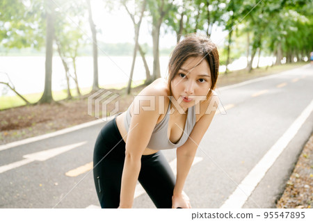 Asian woman wearing sportswear and tired engaged in fitness in public park 95547895