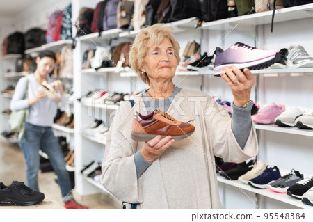Old lady shopping in shoestore Old lady shopping in shoestore 95548384