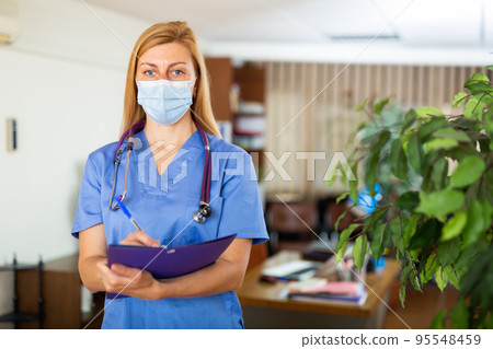 Female doctor in face mask standing in medical office 95548459