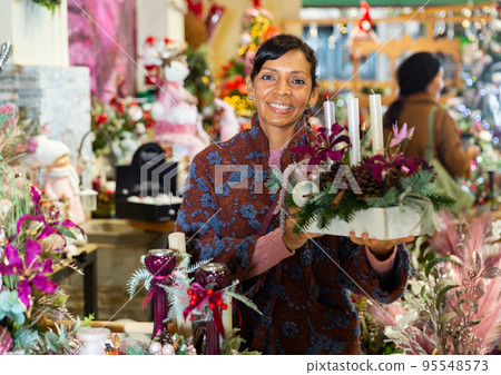 Latin American woman chooses a Christmas composition with candles Latin American woman chooses a Christmas composition with candles 95548573