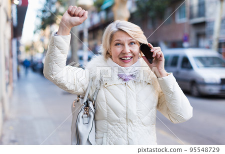 Female talking on mobile phone outdoor and raise hand up Female talking on mobile phone outdoor and raise hand up 95548729