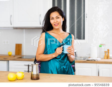 Portrait of positive woman in nightdress with mug of coffee 95548839