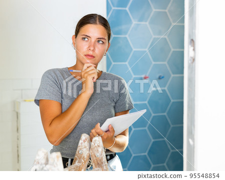 Young woman makes notes on paper while standing in the bathroom Young woman makes notes on paper while standing in the bathroom 95548854