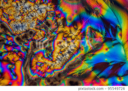 Extreme macro photograph of Vitamin C crystals forming abstract modern art patterns, when illuminated with polarized light, under a microscope objective with 10x magnification 95549726