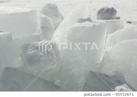 Transparent blue ice hummocks on lake Baikal shore. Siberia winter landscape view. Snow-covered ice of the lake 95552671