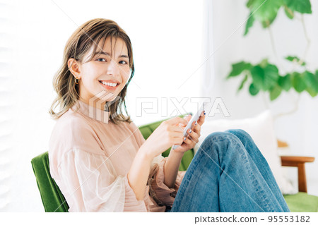 坐在沙發上拿著智能手機的年輕女人 95553182