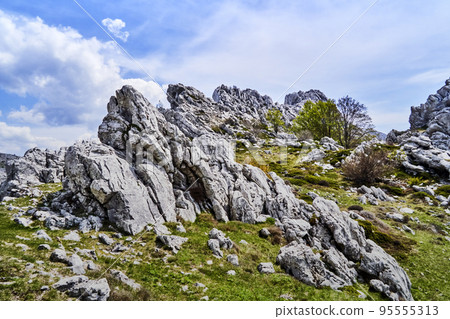 Rock formation of light limestone under blue-white sky in Velebit mountains in Dalmatia, Croatia 95555313