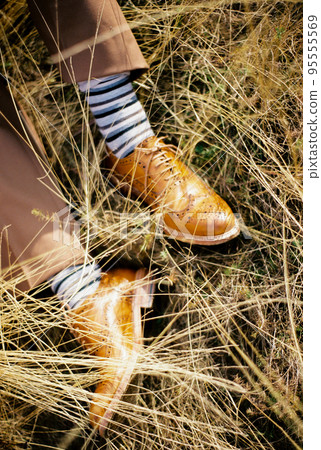 Male feet in yellow leather shoes on dry grass Male feet in yellow leather shoes on dry grass 95555569
