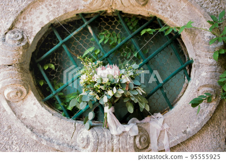 Wedding bouquet on a barred window in the garden Wedding bouquet on a barred window in the garden 95555925