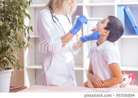 child at a pediatrician's appointment, the doctor checks the boy's throat 95556894