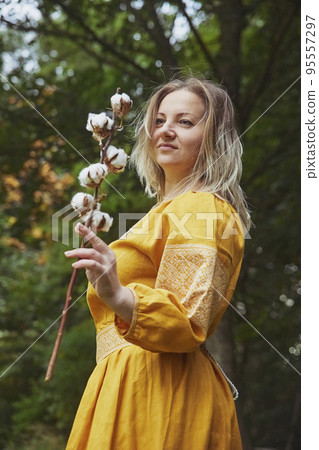 beautiful Ukrainian woman in embroidered dress holds a sprig of cotton 95557297