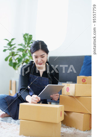 Startup small business entrepreneur of freelance Asian woman smiling and using tablet computer with Cheerful success of item online marketing packaging box and delivery SME idea concept. Startup small business entrepreneur of freelance Asian woman smiling and using tablet computer with Cheerful success of item online marketing packaging box and delivery SME idea concept. 95557759