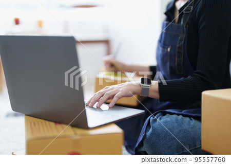 Startup small business entrepreneur of freelance Asian woman smiling and using laptop computer with Cheerful success of item online marketing packaging box and delivery SME idea concept. Startup small business entrepreneur of freelance Asian woman smiling and using laptop computer with Cheerful success of item online marketing packaging box and delivery SME idea concept. 95557760