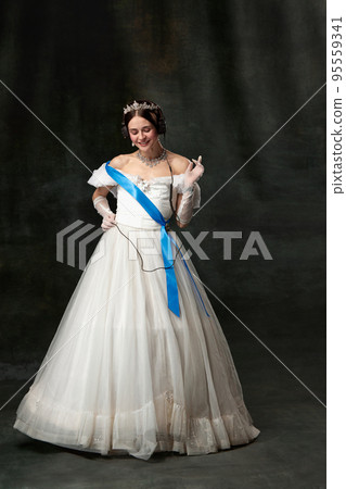 The favorite music. Elegant woman, royal person, queen or princess in white medieval outfit listening to music on dark vintage background. The favorite music. Elegant woman, royal person, queen or princess in white medieval outfit listening to music on dark vintage background. 95559341