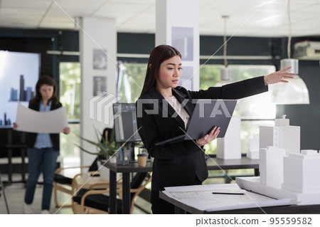 Architect working with city construction project in architecture office, modeling 3d building, using software on laptop. Designer engineering, real estate worker standing with computer Architect working with city construction project in architecture office, modeling 3d building, using software on laptop. Designer engineering, real estate worker standing with computer 95559582