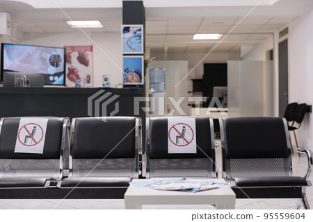 Solitaire lobby seats at medical center. Uncrowded emergency room waiting area at modern clinic. Empty hospital corridor waymarked to keep social distance avoiding coronavirus. 95559604