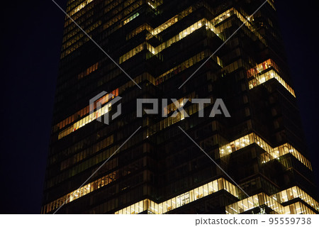 Office building facade with illuminated windows at night city. Warsaw city downtown district with skyscraper facade. Night city panorama Office building facade with illuminated windows at night city. Warsaw city downtown district with skyscraper facade. Night city panorama 95559738