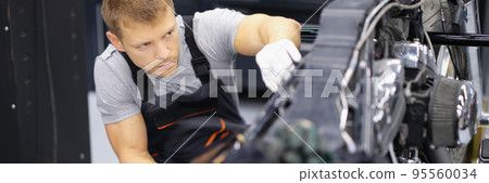 Concentrated serious handyman with tool fix damaged motorbike in garage 95560034