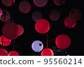 red and white modern pendant lamps, plastic spherical chandeliers. Illuminated lamp hanging against black background. 95560214