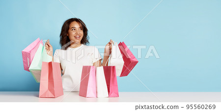 Portrait of happy young woman with many shopping bags isolated over blue background 95560269