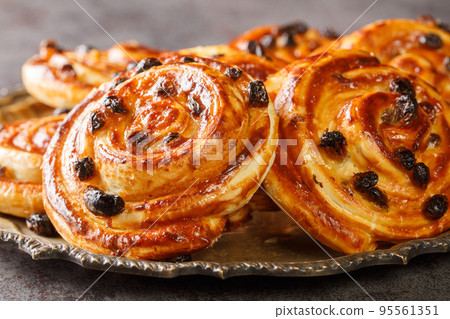 Delicious pain aux raisins spiral buns with raisins and custard close-up in a plate. horizontal 95561351