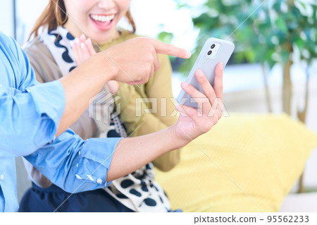 A couple looking at a smartphone in the living room A couple looking at a smartphone in the living room 95562233