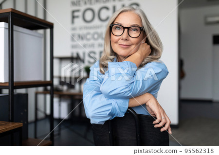 close-up portrait of a strong female leader 50 years old sitting on a chair against the backdrop of 95562318