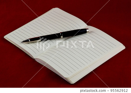 Open Notepad and Roller Ball Pen on a Red Table Cover 95562912