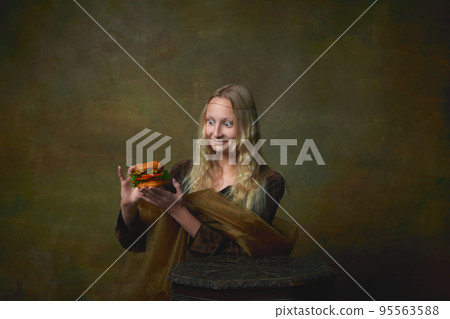 Surprised young girl as Mona Lisa picture tasting burger over dark vintage background. Retro style, art, fashion, comparison of eras concept. Surprised young girl as Mona Lisa picture tasting burger over dark vintage background. Retro style, art, fashion, comparison of eras concept. 95563588