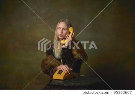 Shocked young girl as Mona Lisa picture talking on retro phone over dark vintage background. Retro style, art, fashion, comparison of eras concept. Shocked young girl as Mona Lisa picture talking on retro phone over dark vintage background. Retro style, art, fashion, comparison of eras concept. 95563607