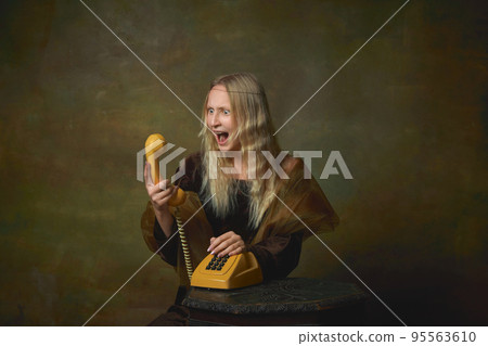Scream. Shocked young girl as Mona Lisa picture talking on retro phone over dark vintage background. Retro style, art, fashion, comparison of eras concept. Scream. Shocked young girl as Mona Lisa picture talking on retro phone over dark vintage background. Retro style, art, fashion, comparison of eras concept. 95563610