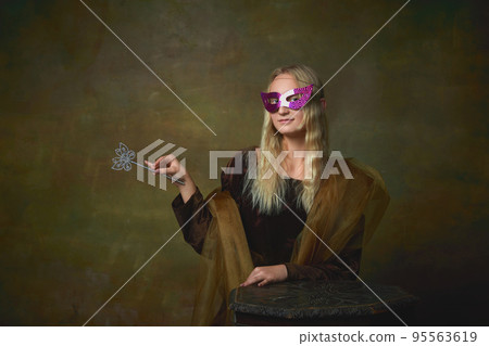 Mask ball. Portrait of young girl as Mona Lisa picture posing over dark vintage background. Retro style, art, fashion, comparison of eras concept. Mask ball. Portrait of young girl as Mona Lisa picture posing over dark vintage background. Retro style, art, fashion, comparison of eras concept. 95563619