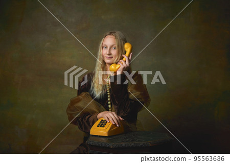 Ring. Elegant young girl with long blonde hair wearing medieval dress like Mona Lisa replica over dark vintage background. Vintage style, art, fashion, comparison of eras concept. Ring. Elegant young girl with long blonde hair wearing medieval dress like Mona Lisa replica over dark vintage background. Vintage style, art, fashion, comparison of eras concept. 95563686