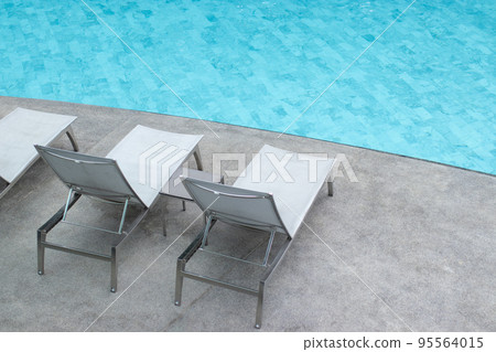 Gray pool lounge chairs by swimming pool. 95564015