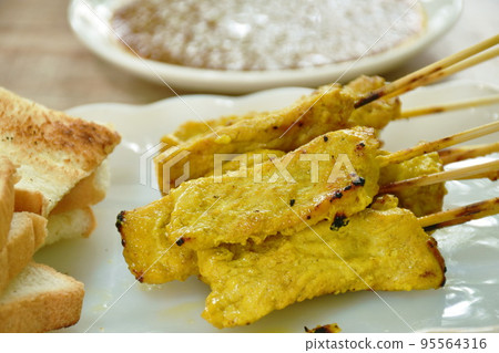 grilled pork satay couple bread dipping with sweet peanut sauce and pickled vegetable  Indonesian food on plate 95564316