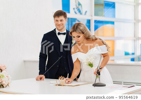 groom and bride put signatures in documents at the official wedding ceremony groom and bride put signatures in documents at the official wedding ceremony 95564619