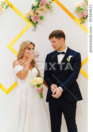 the groom and the bride drink wine from a big glass at the wedding ceremony 95564621