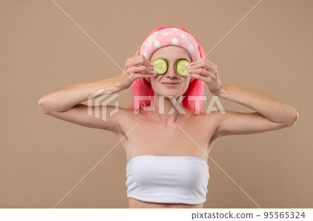 Smiling young girl using cucumber for face care 95565324