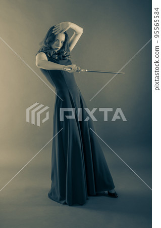 Attractive young princess girl defends herself with a sword. Halloween sepia toned 95565584