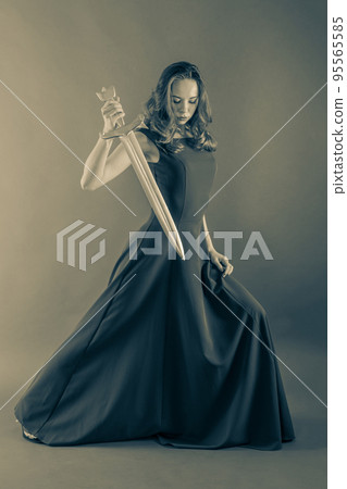 Attractive young princess girl attacking with a sword. Halloween sepia toned Attractive young princess girl attacking with a sword. Halloween sepia toned 95565585