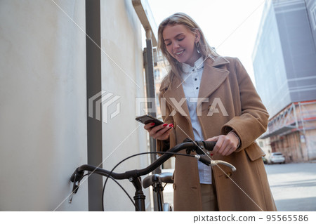 Woman in a beige coat searching for a route via gps Woman in a beige coat searching for a route via gps 95565586