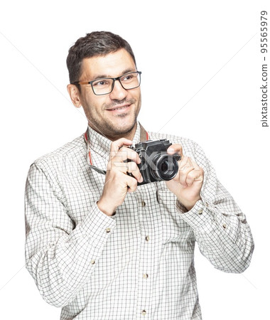 Handsome man in glasses and a plaid shirt, smiling and taking pictures with an vintage camera Handsome man in glasses and a plaid shirt, smiling and taking pictures with an vintage camera 95565979