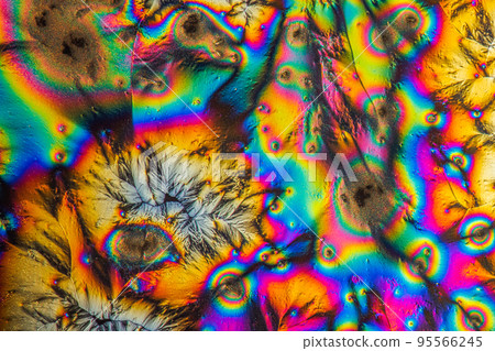 Extreme macro photograph of Vitamin C crystals forming abstract modern art patterns, when illuminated with polarized light, under a microscope objective with 10x magnification 95566245